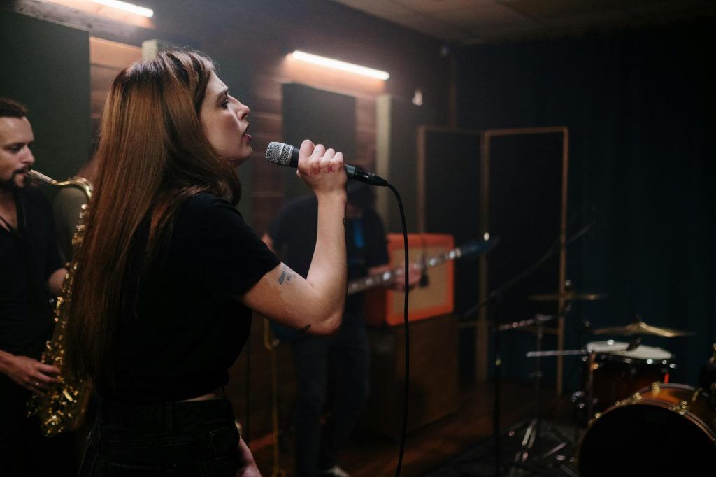 Indie band rehearsing in a music studio, featuring a female singer with a microphone.
